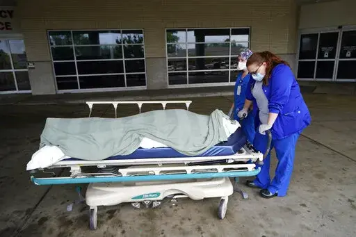 Medical staff prepare to move the body of a deceased COVID-19 patient to a funeral home van at the Willis-Knighton Medical Center in Shreveport, La., Wednesday, Aug. 18, 2021. Data released by the Centers for Disease Control and Prevention in April 2022 confirms that 2021 was the deadliest year in U.S. history. (AP Photo/Gerald Herbert, File)